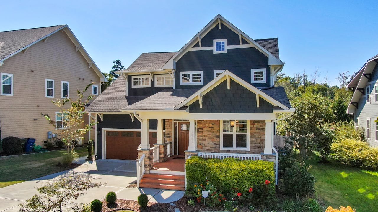 Modern residential home with a well-maintained front yard and landscaping, showcasing a combination of stone and wood exterior, located in a suburban neighborhood, representing quality real estate options in Rochester Hills, MI.