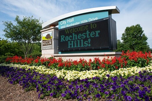 Green arched Rochester Hills city entrance sign above a flower bed in Rochester Hills, Michigan